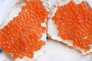 Red salmon caviar on bread and butter. A sandwich with caviar and butter on a plate. photo
