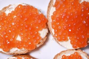 Red salmon caviar on bread and butter. A sandwich with caviar and butter on a plate. photo