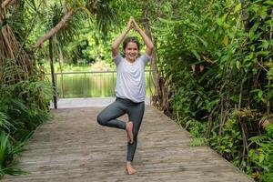 Little girl child doing yoga exercise relax in the park. stretching on the grass summer day photo