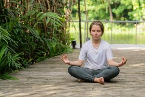 pequeño niña niño haciendo yoga ejercicio relajarse en el parque. extensión en el césped verano día foto