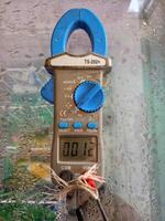 Ampere pliers are being used to measure the voltage in the freezer photo