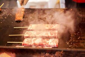 Closeup barbecue Kobe beef stick on hot pan. One of tourist popular snack food at Kuromon market ,Osaka city, Japan photo