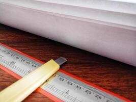 Paper, cutter and ruler on the work table with angels close up photo