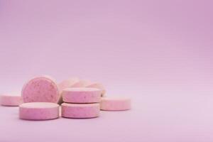 Close-up of pink pills on a pink pastel background. Selective focus. Theme is treatment of diseases, medicine and pharmaceuticals. photo