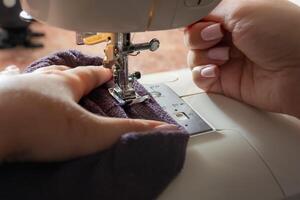 de cerca de un mujer manos de coser en un de coser máquina foto