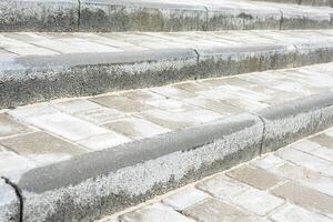 Concrete steps from paving slabs and curb in a park, close-up photo with selective focus.