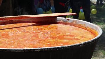 Tomato soup with pasta is a dish of Polish cuisine. Hot Zupa pomidorowa in a large cauldron at the field kitchen at a food fair. A popular soup made from grated tomatoes in their own juice. video