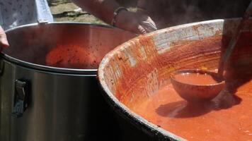 Tomato soup with pasta is a dish of Polish cuisine. Hot Zupa pomidorowa in a large cauldron at the field kitchen at a food fair. A popular soup made from grated tomatoes in their own juice. video