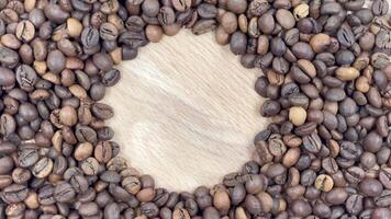 Space for your logo or text against a backdrop of rotating freshly roasted coffee beans on a wooden background. Copy space, flat layout. video