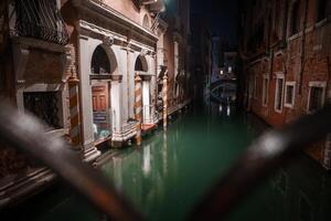 romántico noche ver de Venecia canal con iluminado arquitectura y reflexiones foto