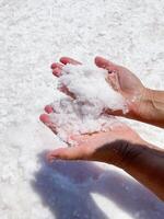 Womans hands with salt in her hands against the backdrop of salt lake. photo