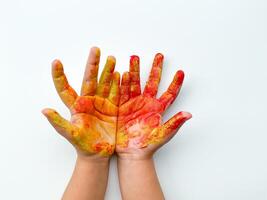 Childrens hands painted with yellow and red paint on white background. photo