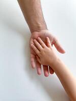 adulto y niño sostener su manos juntos. padres día niño da mano a adulto foto