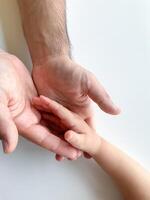 adulto y niño sostener su manos juntos. padres día niño da mano a adulto foto