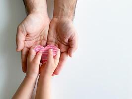 child gives adult small red paper heart. Fathers Day. Family, love, parents photo