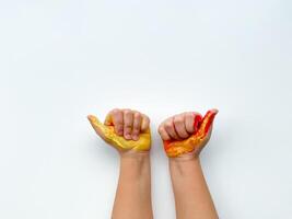 Childrens hands painted with yellow and red paint on white background. photo