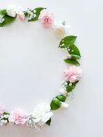 Round frame of pink and white carnations, leaves photo