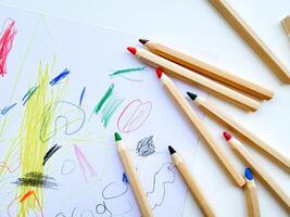 Colored pencils on the background of a childs drawing. Top view. photo