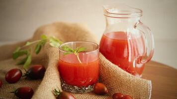 hausgemacht frisch gedrückt Tomate Saft mit Fruchtfleisch im ein Glas Karaffe, auf ein hölzern Tisch. video