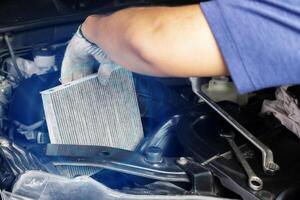 Car air conditioner system maintenance, Hand mechanic holding car air filter to check for clean dirty or fix repair heat have a problem or replace new or change filter. photo