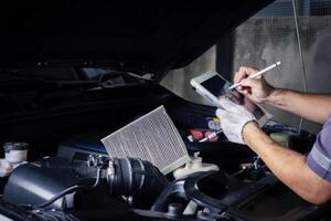 The mechanic checks the engine using tablet computer technology. Complete with wrench tool Auto mechanic working in the garage. Repair service. photo