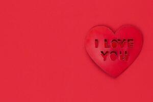 Valentine card, Inscription I love you, red heart shape on red background copy space photo