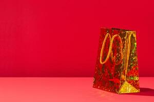 One Yellow bright gift paper shopping bag on red background. Copy space for text photo