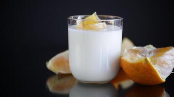 hausgemacht Süss Joghurt im ein Glas mit Orangen isoliert auf schwarz Hintergrund video