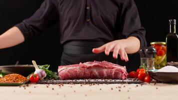 Close-up of falling tasty beef steak in kitchen, super slow motion, camera movement. Chef cooks beef steak, sprinkling with salt on a background of professional kitchen. High quality 4k footage video