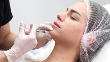 injektion procedur. de kosmetolog långsamt och försiktigt injicerar fyllmedel in i de klient haka. reklam begrepp för ansiktsbehandling vård, ungdom och skönhet video