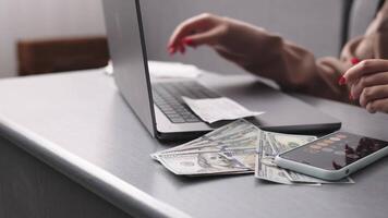 une femme compte les dépenses sur une ordinateur portable, calcule finances et attend à faire achats. concept de une affaires femme derrière une portable. video