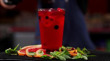 Close up of a professional bartender is mixing an alcoholic cocktail with professional crystal long lasting ice cubes to customers at the bar or disco club. Professional bartender masterly creating video