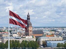 panorama de riga ciudad con un grande letón bandera en primer plano foto