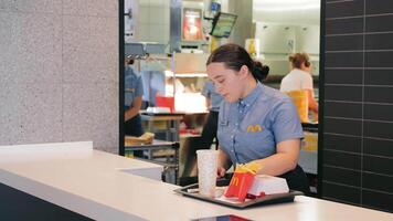 ukraina lviv 28.01.2024 mcdonalds anställd tjänande ordning, en mcdonalds anställd är lämnandet över ett beställa med en dryck och frites på de disken. video