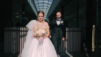 sofisticado Boda dúo en atrio, novia y novio listo en un iluminado por el sol atrio, exudando sofisticación. video