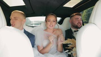 exuberante Casamento festa cantando dentro luxo carro, noiva e noivo com melhor homem cantando e rindo dentro uma luxo carro. video