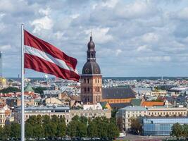 panorama de riga ciudad con un grande letón bandera en primer plano foto
