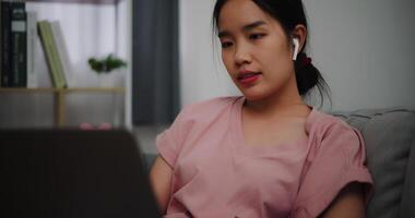 Portrait of Young woman sitting on sofa while working with laptop at home office. photo