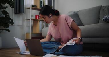 Portrait of Young woman sitting on the floor working with a laptop and checking workpaper at home office. photo