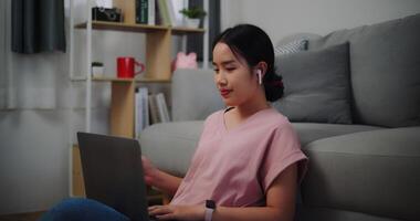 Portrait of Young woman sitting on the floor leaning against a sofa working with a laptop at home office. photo