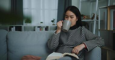 retrato de contento joven asiático mujer Bebiendo Mañana café o té y leyendo en vivo habitación a hogar en fin de semana. ocio y estilo de vida, gratis hora foto