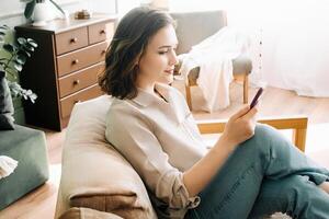 Digital Delight. Smiling Millennial Woman Engaged with Smartphone, Reading Messages, Chatting, and Enjoying Internet Surfing. Modern Communication and Social Media Lifestyle Concept. photo