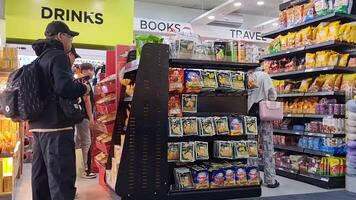 Manila, Philippines on November 2, 2023. Several visitors, male and female tourists are having snacks and drinks that are sold at the minimarket at Ninoy Aquino Airport. Provide books and souvenirs video