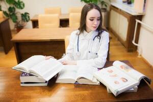 un médico estudiante para libros de texto el estudiar de cirugía por un hermosa niña en el biblioteca foto