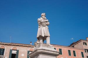Venecia estatua de hombre en largo Saco y sombrero en pie en frente de histórico edificio foto