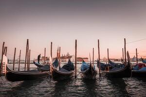 tranquilo puesta de sol escena de góndolas atracado en un sereno canal, reflejando el suave colores de Venecia. foto