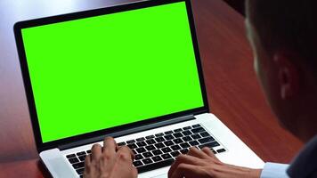 a man is typing on a laptop with a green screen video