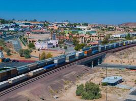 Panoramic View of Colorful Train in Southwestern Desert Landscape with Barstow Town and Mountains photo