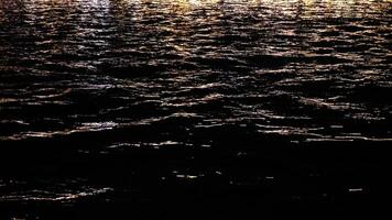 Abstract reflections of sparkling lights on the sea surface in night time video