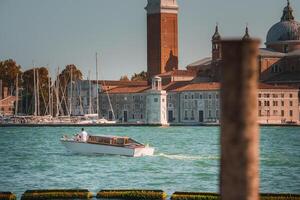 White boat floating in front of iconic clock tower in the heart of Venice photo